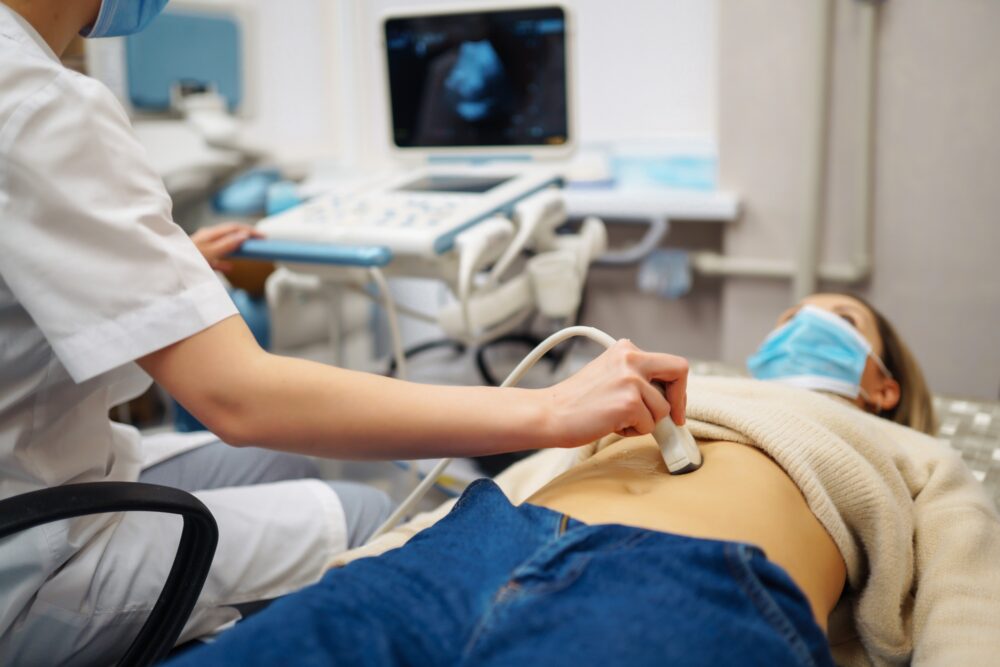 Doctor makes patient women abdominal ultrasound. Ultrasound Scanner in hands of doctor. Diagnostics.